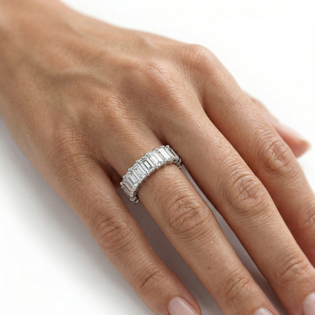 Emerald Eternity Ring in platinum worn on ring finger