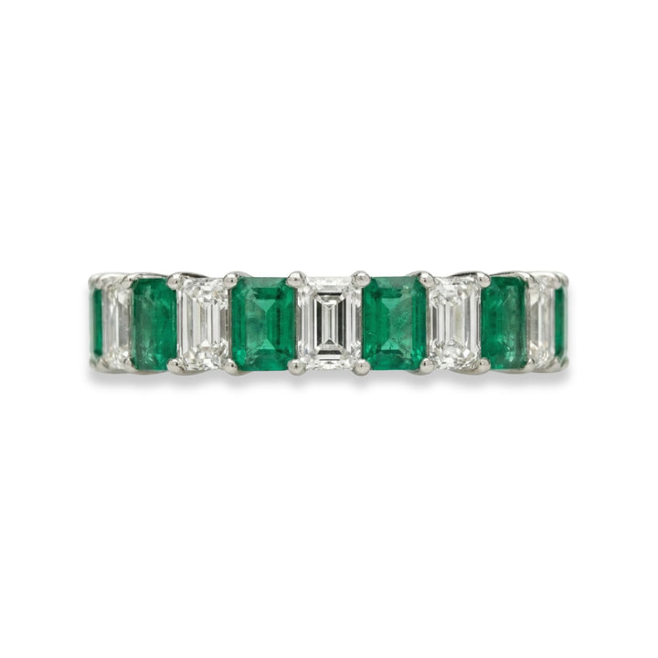 Platinum emerald cut eternity ring with alternating white diamonds and green emeralds