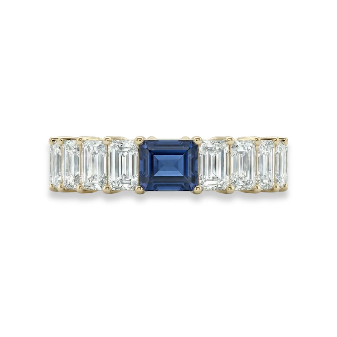 18K yellow gold emerald cut eternity ring with blue sapphire center stone