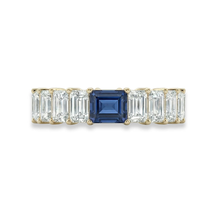 18K yellow gold emerald cut eternity ring with blue sapphire center stone